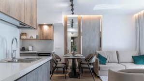 Een moderne keuken met een centraal eiland, een eethoek met stoelen en een bank met blauwgroene kussens.
