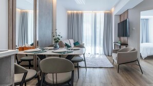 Een moderne hotelkamer met een eethoek, een bank, een televisie en een bed.