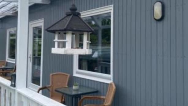 A blue house with a covered porch, a hanging lantern, and a small table with chairs. - Your favorite place in Cuxhaven: Double room with terrace (Cuxhaven)