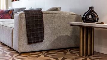 A sofa with a plaid throw blanket, a vase, and a geometric patterned floor.