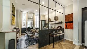 Une cuisine moderne dotée d’un îlot central, d’un parquet en bois disposé en motif à chevrons et d’une cloison noire.