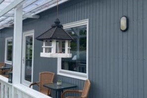 Une maison bleue avec un porche couvert, une lanterne suspendue et une petite table entourée de chaises.