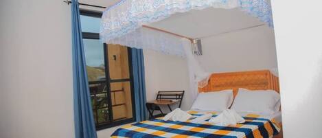 A single bed with a checkered bedspread, a wooden headboard, and a canopy with lace detailing.