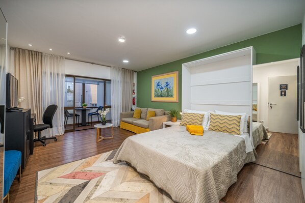 Een moderne hotelkamer met een groot bed, een bureau, een sofa en uitzicht.