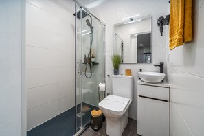 Een moderne badkamer met een douchecabine van glas, een toilet, een wastafel en een spiegel.