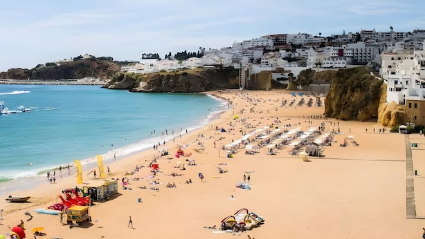 A coastal beach with a sandy shore, a small boat, and a building complex in the background. - Studio 'Zizas House' with Wi-Fi and Air Conditioning (Portimão)