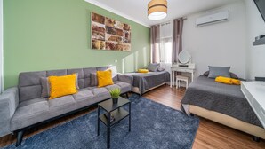Een moderne, goed verlichte kamer met een bank, een bed, een bureau en een kleine tafel met een plant.