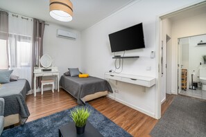 Een moderne hotelkamer met een bed, bureau, televisie en een badkamer, zichtbaar door een open deur.