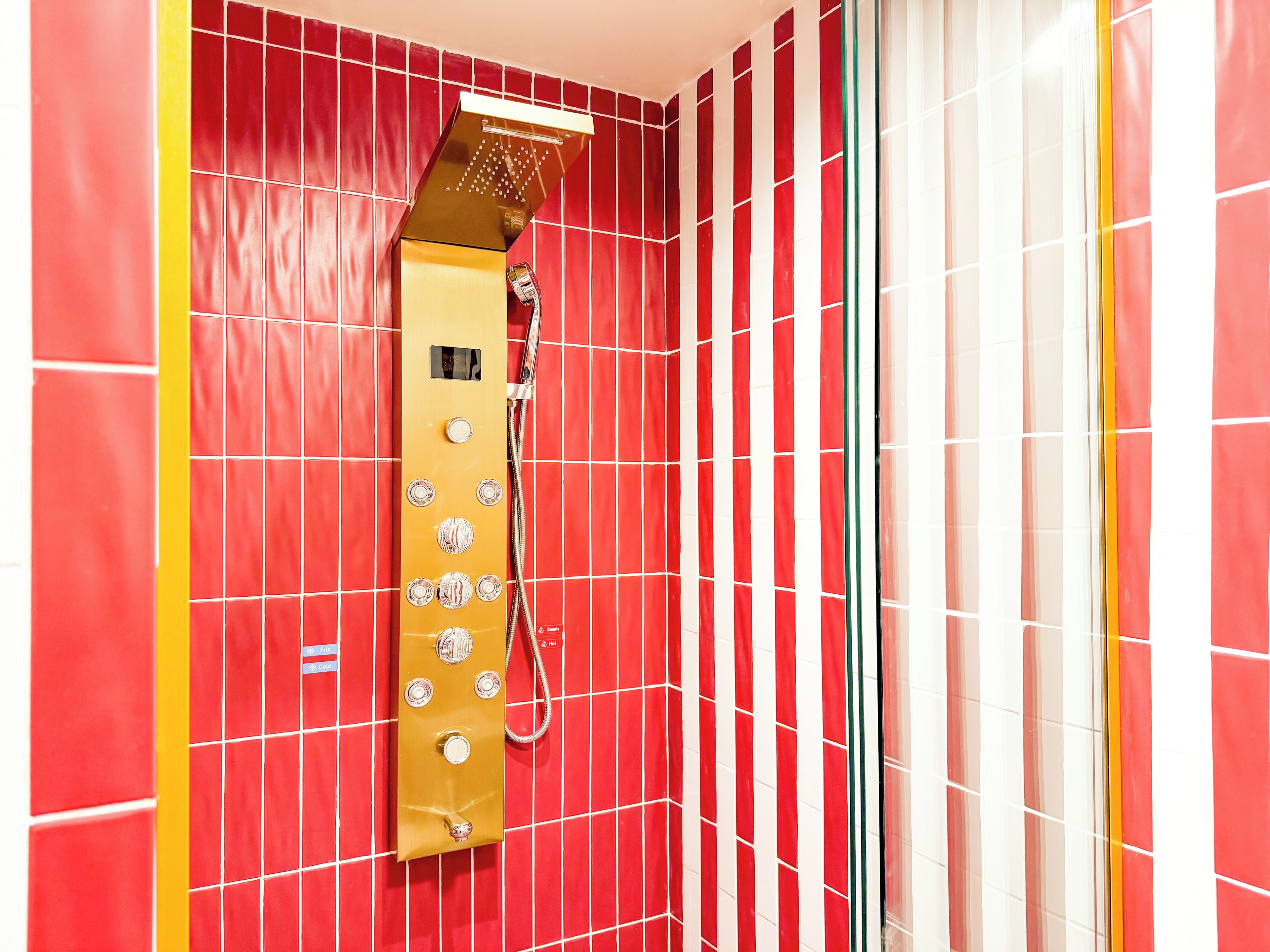 Una ducha con panel de control y cabezal de ducha manual.
