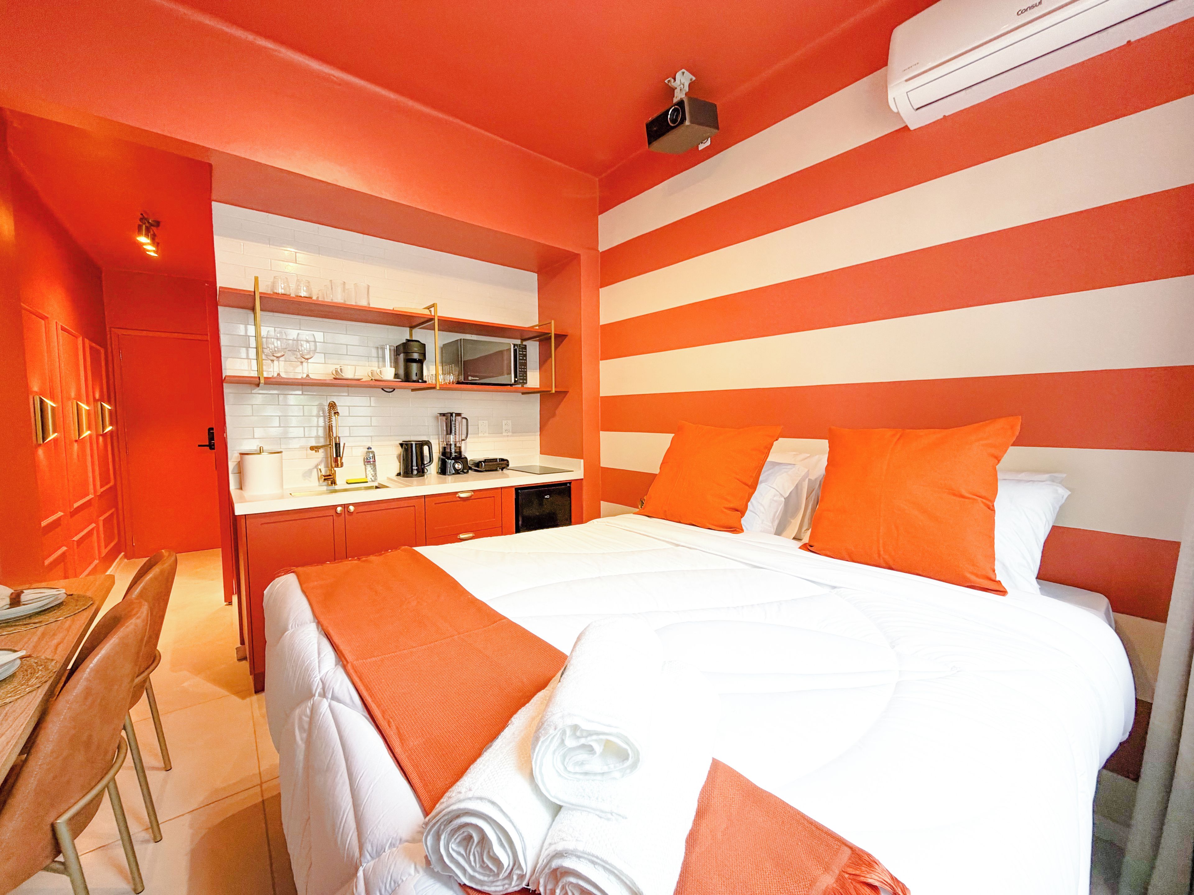 A hotel room with a bed, a desk, and a kitchenette.
