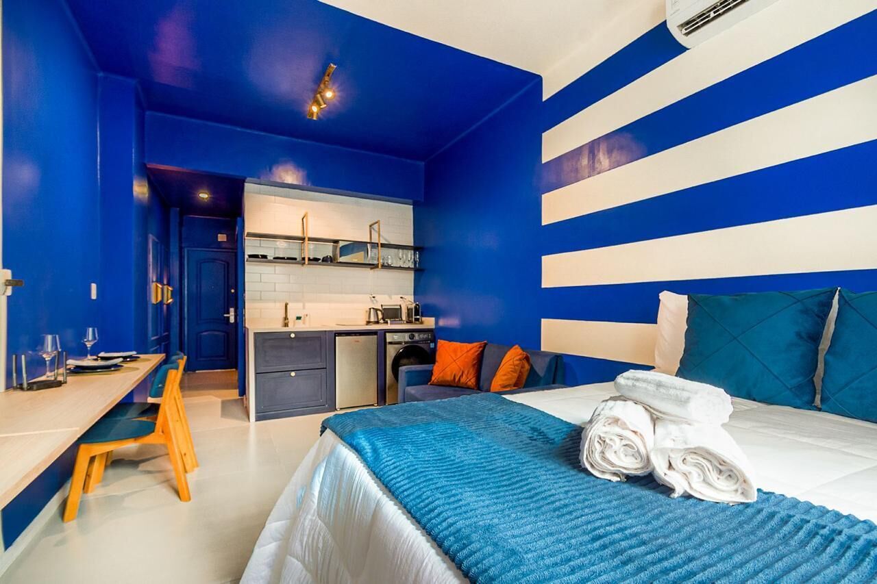 A hotel room with a bed, a desk, and a kitchenette.