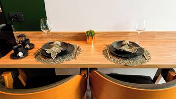 Una mesa de comedor dispuesta con platos, cubiertos y vasos, con dos sillas a cada lado.