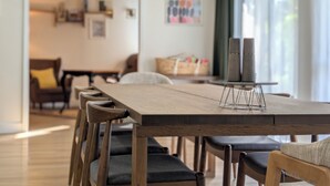 Uma área de refeições com uma mesa de madeira comprida, várias cadeiras e um castiçal.