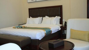 Una habitación de hotel con una cama grande, una mesita de noche, una silla y una pequeña mesa.