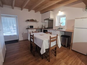 Eine Küche mit Esstisch, Stühlen, einer Mikrowelle, einem Spülbecken und einem Kühlschrank.