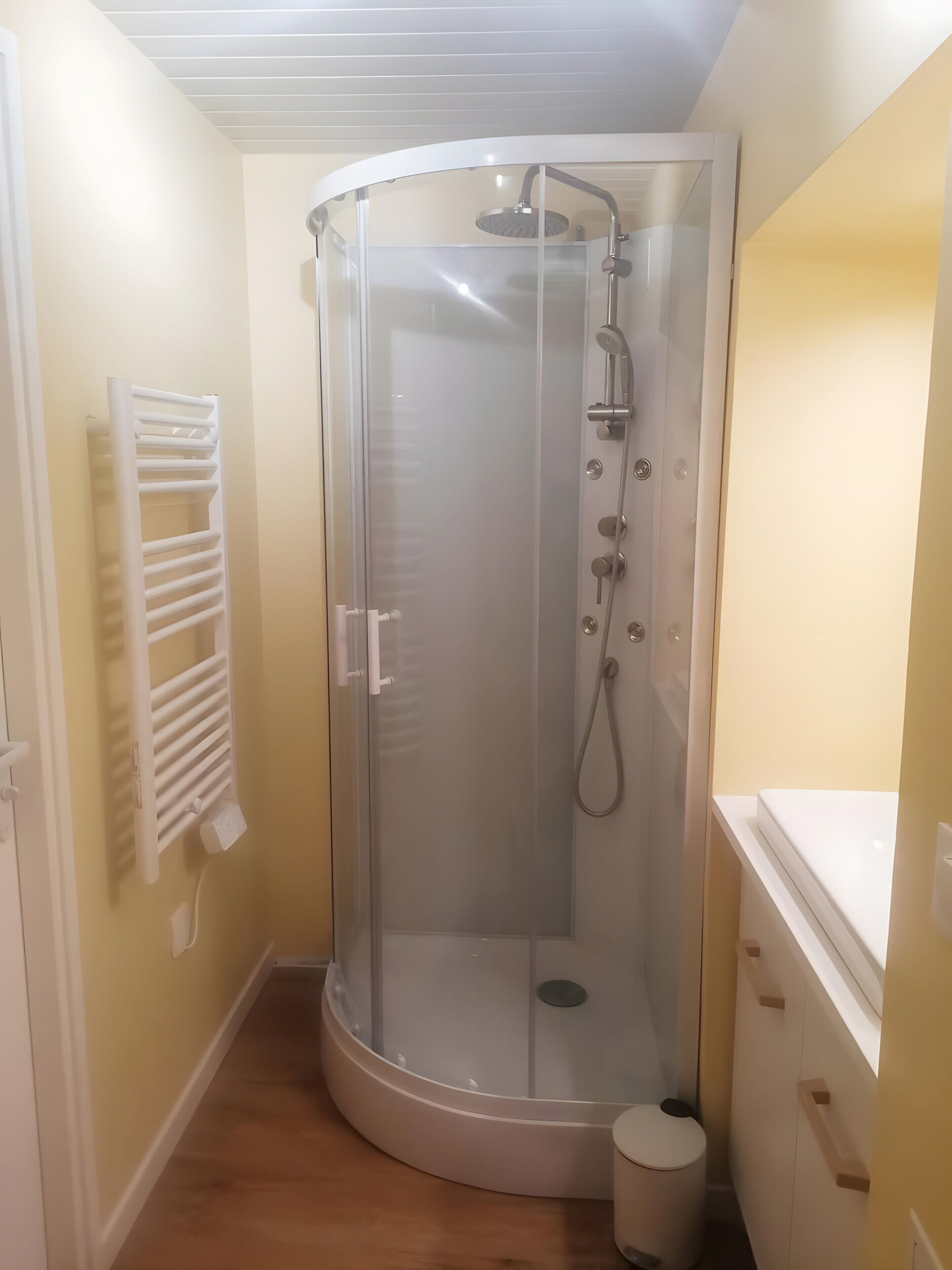 A glass-enclosed shower stall with a handheld showerhead and a handheld shower attachment.