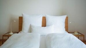 A neatly made bed with white bedding and two bedside lamps on wooden nightstands. - Gästehaus Elena (Kassel)
