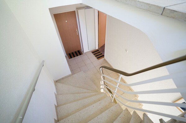 A staircase with a handrail, leading to a room with a door and a small step. - Gästehaus Elena (Kassel)