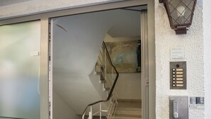 A hotel entrance with a sliding glass door, a staircase, and a wall-mounted intercom. - Gästehaus Elena (Kassel)