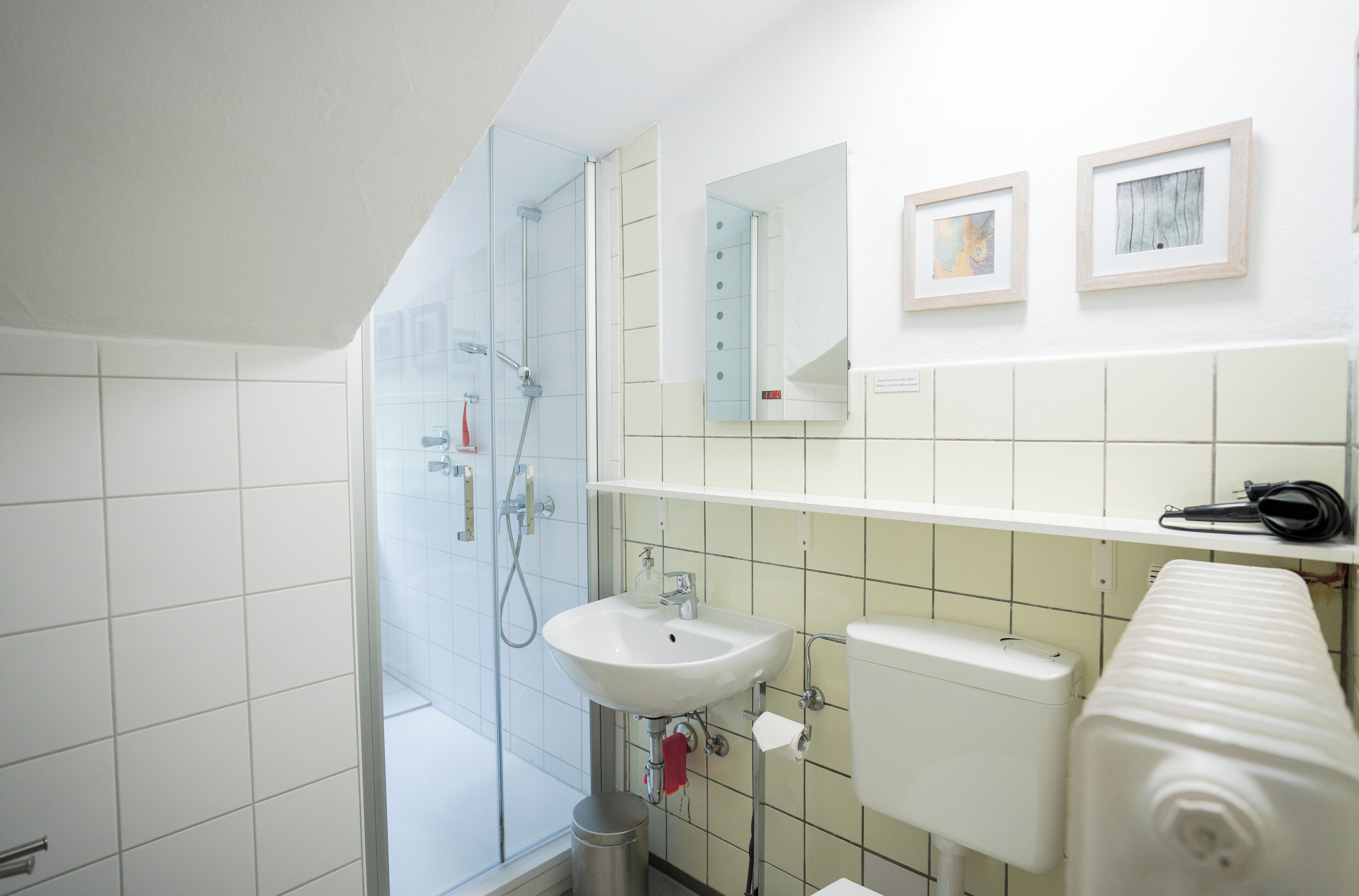 Een badkamer met een douche met glazen wand, een wit wastafel, toilet en handdoekhouder.