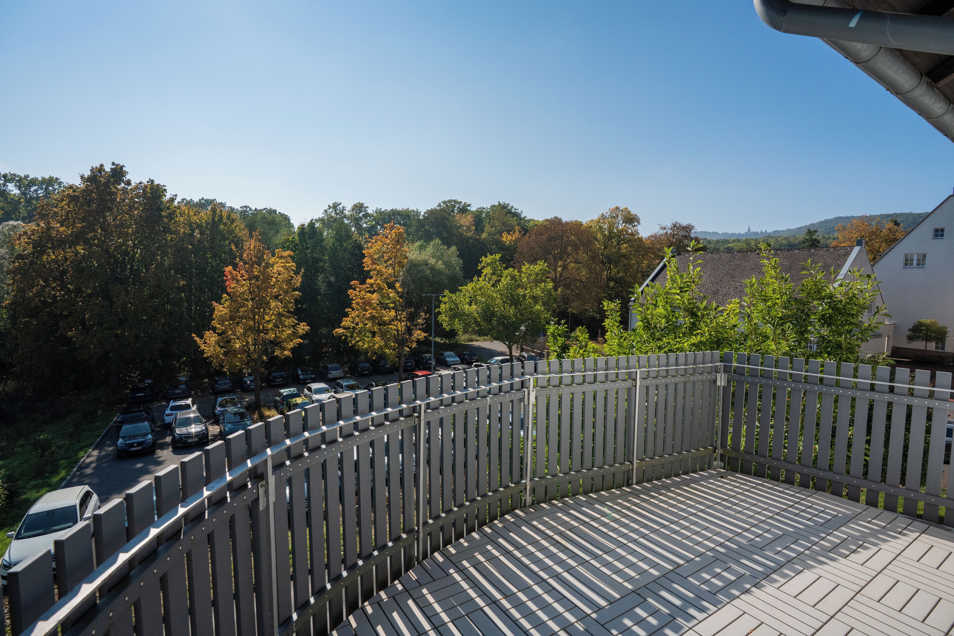 A balcony with a view of parked cars and trees.