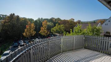 A balcony with a view of parked cars and trees.