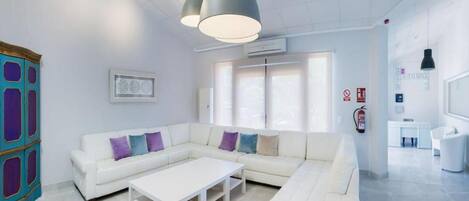 A modern, well-lit living area with a white sectional sofa, a coffee table, and pendant lighting.