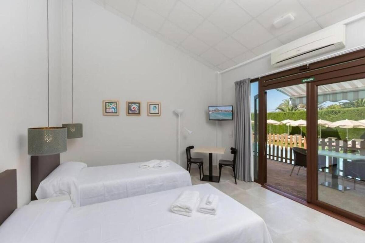 Une chambre d’hôtel avec deux lits, une télévision, une petite table avec des chaises et une vue sur l’espace extérieur.