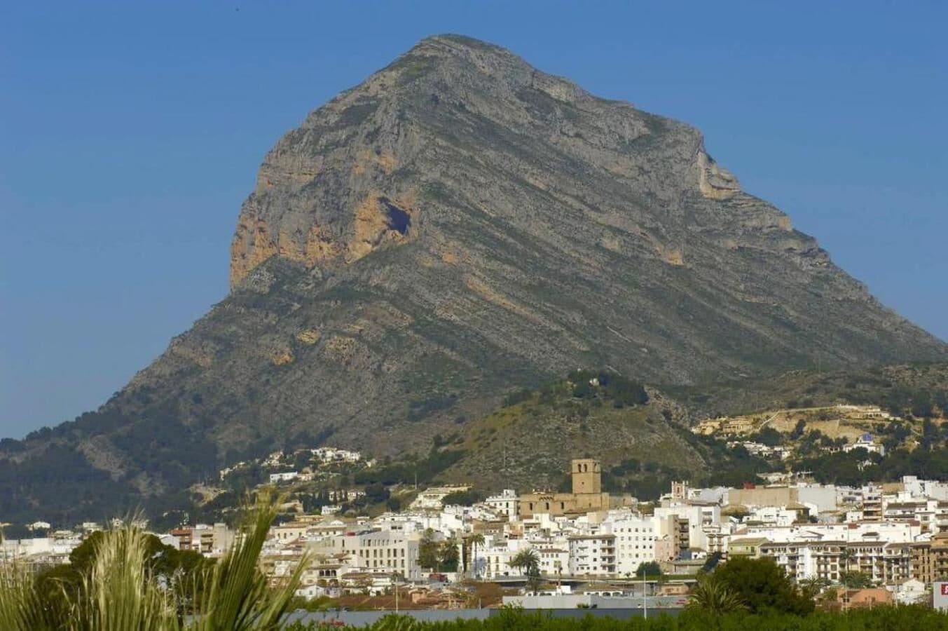 A mountain with a town at its base, featuring a prominent church and residential buildings.