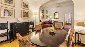 Un coin repas avec une table ronde, des chaises, une commode noire et des œuvres d’art encadrées accrochées aux murs.
