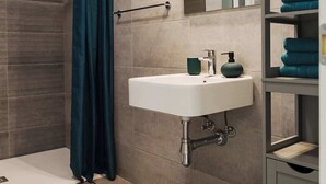 Een moderne badkamer met een douche, wastafel en spiegel.