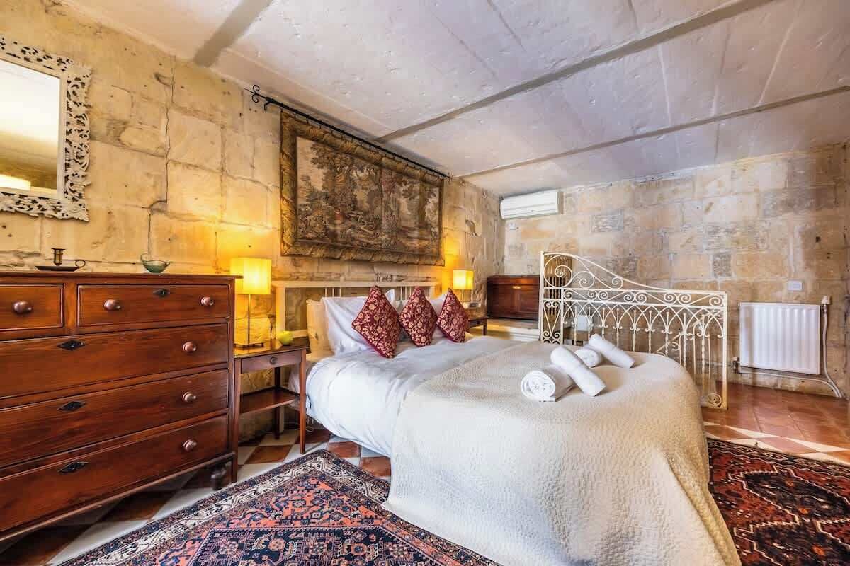 Un dormitorio con una cama grande, un aparador de madera y una pared de piedra.