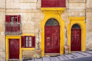 A building with three red doors, each with a small balcony above. - Palazzo San Pawl - The Villhena Suite (Valletta)