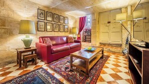Un salon chaleureux avec un canapé rouge, une table basse en bois, des tapis à motifs et des tableaux encadrés accrochés au mur.