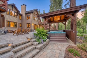 Un edificio de varios pisos con un patio, mobiliario exterior, jacuzzi y una pérgola de madera.