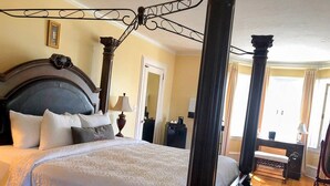 A four-poster bed with a dark headboard, multiple pillows, and a matching footboard. - TTR - Princess Grace (Pembroke)