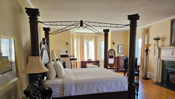 A spacious bedroom with a four-poster bed, wooden flooring, and a fireplace. - TTR - Princess Grace (Pembroke)