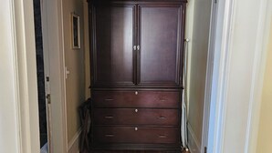 A hallway with a dark wooden wardrobe, a door on the left, and a ceiling light fixture. - TTR - Princess Grace (Pembroke)