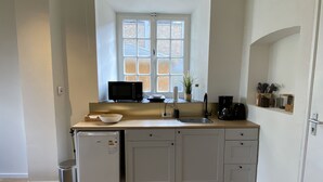 A compact kitchen with a window, a microwave, a sink, and a small refrigerator. - Modern Studio 3 in Historic Abbey (Cadier en Keer)