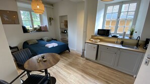 A compact living space with a bed, a dining table, a kitchen area, and a small seating area. - Modern Studio 3 in Historic Abbey (Cadier en Keer)