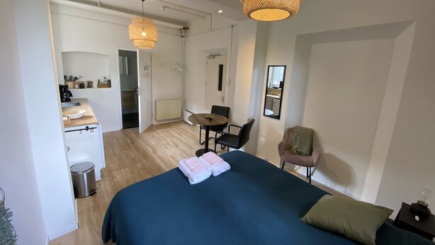 A modern hotel room with a large bed, a dining area, and a kitchenette. - Modern Studio 3 in Historic Abbey (Cadier en Keer)