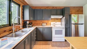 Une cuisine avec des lambris en bois, un évier, une cuisinière et un réfrigérateur.