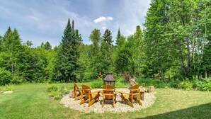 Un espace extérieur circulaire aménagé avec des chaises Adirondack en bois et une table centrale, le tout entouré d’un cercle de gravier au milieu d’un paysage verdoyant.