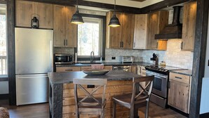 Eine moderne Küche mit Holzschränken, einem Edelstahlkühlschrank, einer Mikrowelle, einem Herd und einem Spülbecken.