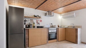 Eine moderne Küche mit eingebautem Ofen, einem Edelstahl-Kühlschrank, Holzschränken und einer Ziegeldecke.