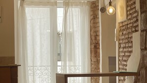 Ein Zimmer mit Steinwand, einem Holztisch, zwei Poufs und einer Hängelampe.
