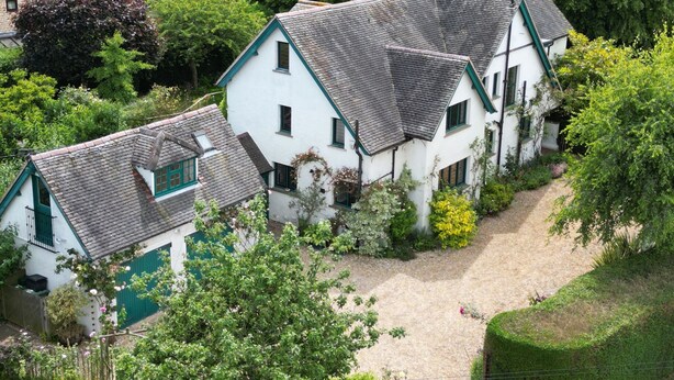 A cluster of white houses with green trim and grey tiled roofs, surrounded by lush greenery. - White House (Chipping Campden)