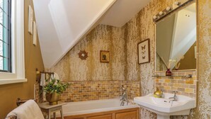 A bathroom with a bathtub, a sink, a mirror, and a window. - White House (Chipping Campden)