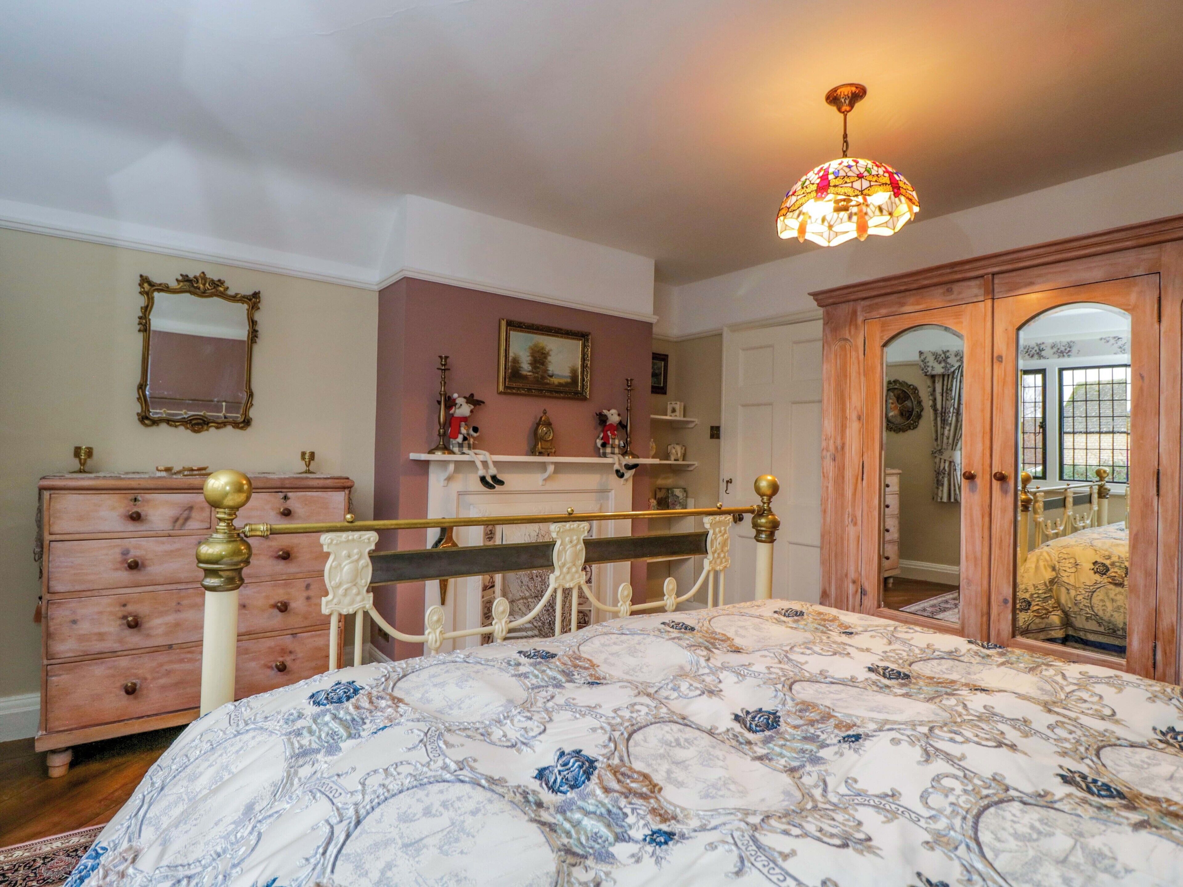 Een slaapkamer met een bed, een kaptafel, een spiegel en een deur naar een andere kamer.