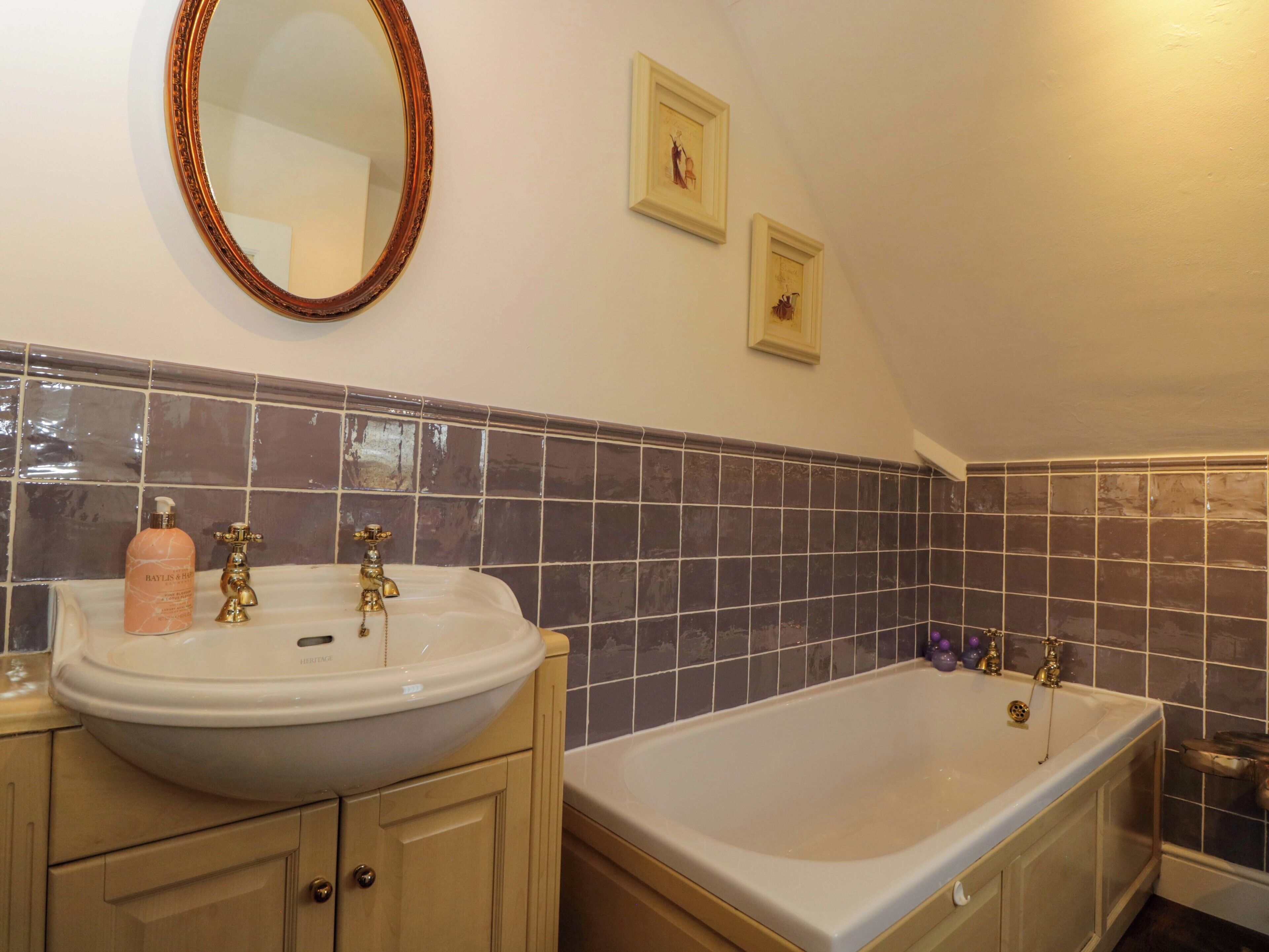 A bathroom with a sink, mirror, and bathtub.